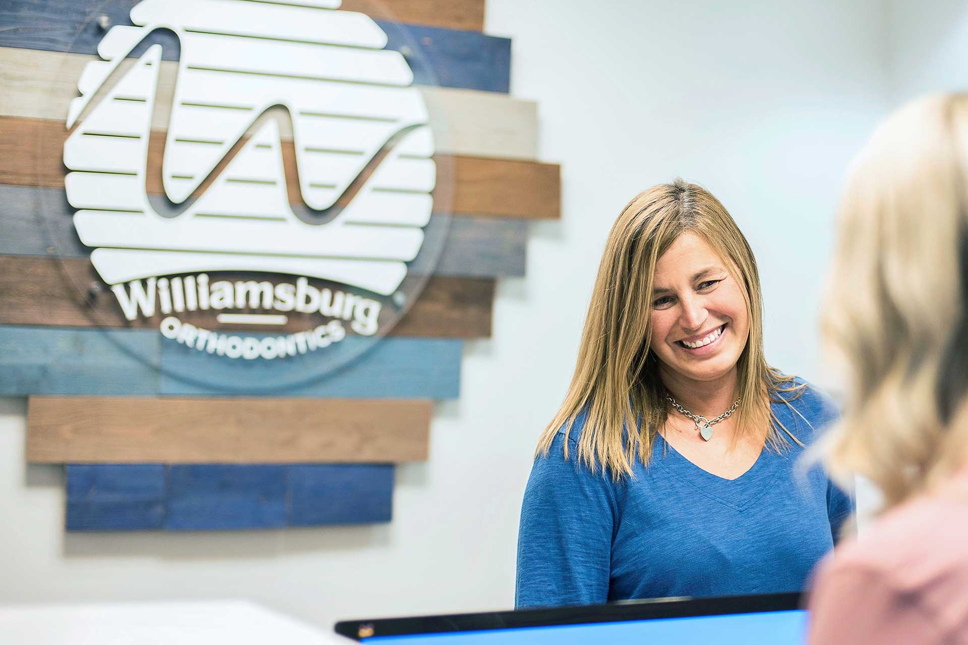 Smiling receptionist at the front desk of orthodontics practice